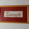 Zweigelt, © Familie Fleischmann Stickbild mit dem Wort 'Zweigelt' in einem Holzrahmen.