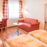 Gästezimmer, © Fam. Breitenfelder Gemütliches Gästezimmer mit Doppelbett, rotem Sofa, Schreibtisch, Fernseher und großem Spiegel.