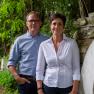Harald & Michaela Breitenfelder, © Tonality Ein Mann und eine Frau stehen nebeneinander auf einem gepflasterten Weg im Freien, umgeben von Bäumen und einer Steinmauer.