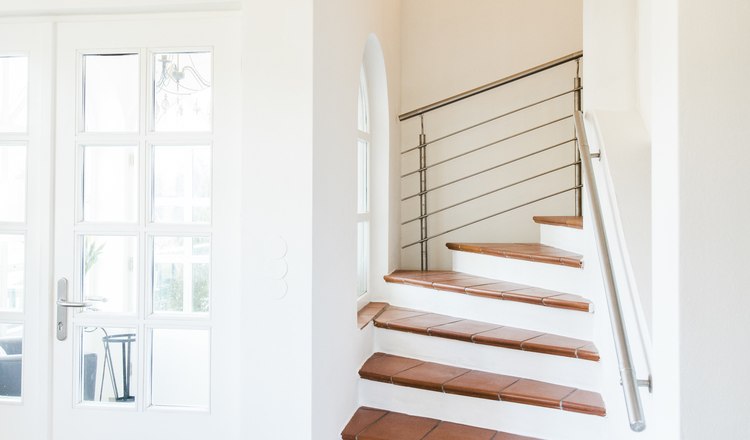 Eingangsbereich, © Agnes Buchmayer Innenansicht eines modernen Treppenhauses mit weißen Wänden und Terrakottafliesen.