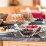 Frühstück, © Fam. Breitenfelder Frühstücksbuffet mit Kuchen, Beeren, Käseplatte und Getränken auf einem Tisch.