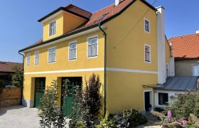 Ferienhaus Karoline, © Fam. Schneider Gelbes zweistöckiges Haus mit rotem Dach und Garten.