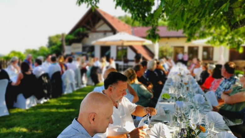 Tafeln im Weinviertel, © Weinstraße Weinviertel Menschen sitzen an langen Tischen im Freien bei einer Veranstaltung.