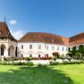 Schrattenthal Schloss, © Stadtgemeinde Schrattenthal Panoramablick auf das Schloss Schrattenthal mit gepflegtem Garten und blühenden Rosen im Vordergrund.
