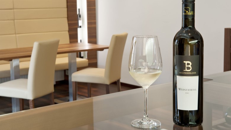 Verkostungsraum, © Seymann Ein Verkostungsraum mit einer Flasche Weißwein und einem gefüllten Weinglas auf einem Tisch.