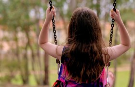Spielplatz, © pixabay Ein Kind schaukelt im Freien, von hinten fotografiert, umgeben von Bäumen.