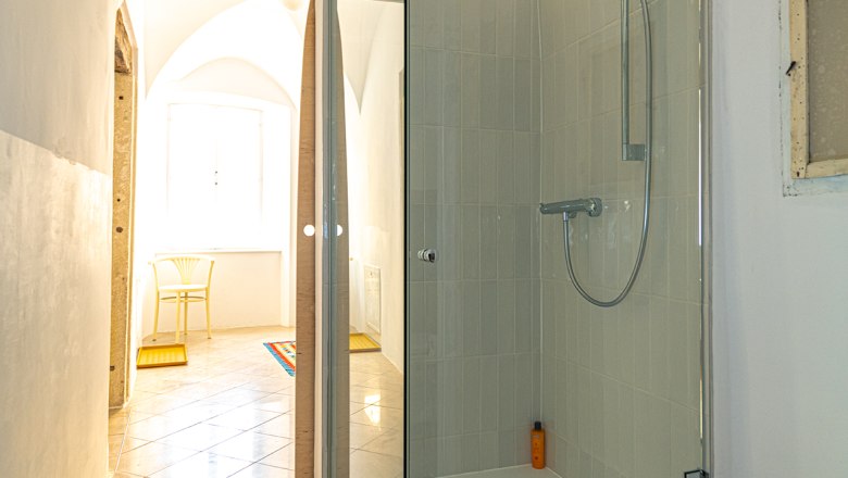 Dusche, © Fam. Heichinger Moderne Dusche mit Glastüren in einem hellen Raum mit gewölbter Decke.