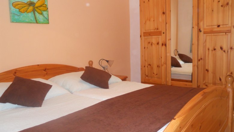 Gästezimmer, © Peter Mödl Ein gemütliches Gästezimmer mit Holzmöbeln, einem Doppelbett und einem Kleiderschrank mit Spiegel.