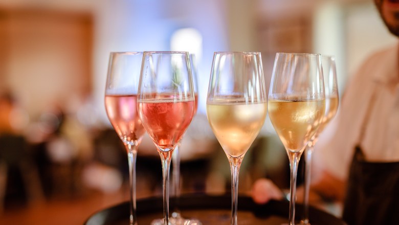 Erfrischender Aperitif, © Weinterrasse Pulkau Nahaufnahme von Sektgläsern auf einem Tablett, gefüllt mit rosé und weißem Sekt.
