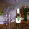Gästezimmer, © Fam. Seher Ein gemütliches Gästezimmer mit einer Flasche Wein, zwei Gläsern und einem Blumenstrauß auf einem Tisch.