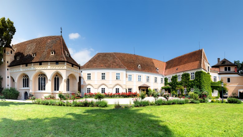 Schrattenthal Schloss, © Stadtgemeinde Schrattenthal Panoramablick auf das Schloss Schrattenthal mit gepflegtem Garten und blühenden Rosen im Vordergrund.