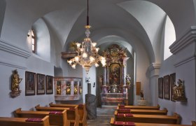 Pfarrkirche Oberretzbach, © Wolfgang Gerzer Innenansicht einer barocken Kirche mit Altar, Gemälden und einem Kronleuchter.