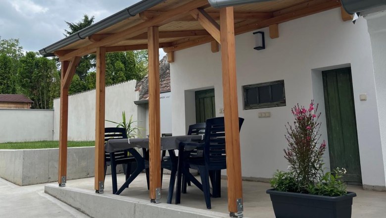 Sitzgelegenheit außen, © Jochen Maurer Überdachte Terrasse mit Tisch und Stühlen, umgeben von Pflanzen.