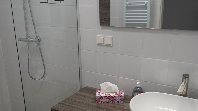 Landhaus Krell, © Weingut Krell Modernes Badezimmer mit Glasdusche, Waschbecken und Spiegel.