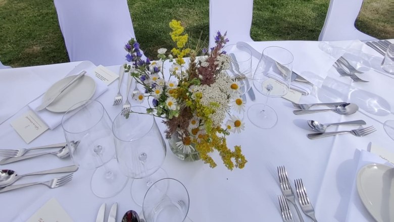 Tafeln im Weinviertel, © Weinviertel Tourismus GmbH Gedeckter Tisch mit Blumenstrauß vor Weinberg und Liegestühlen.