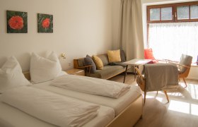 Schlafzimmer, © Familie Fleischmann Ein gemütliches Schlafzimmer mit Doppelbett, Sofa, Tisch und Stühlen. Helle Vorhänge und zwei Blumenbilder an der Wand.