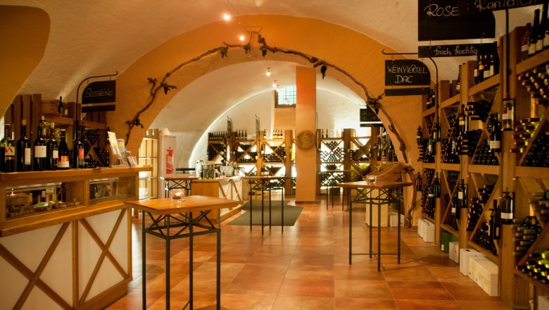 Innenansicht einer Vinothek mit Weinregalen und Tischen.