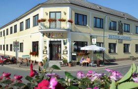 Au&szlig;enansicht des Retzerlandhofs mit Terrasse und Blumen.