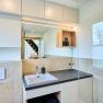 Modernes Badezimmer mit Waschbecken, Spiegel und Fenster.
