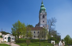 Kirche in Unterretzbach mit grünem Turm und umliegenden Gebäuden.