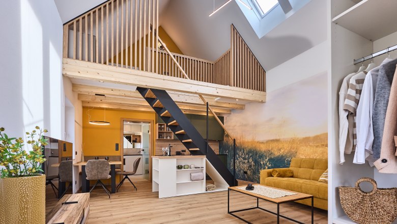 Wiegehaus, © Bernhard Raab Modernes Loft mit offener Galerie, gelbem Sofa und Holzelementen.