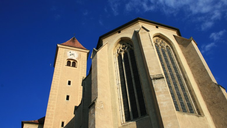 Ansicht der Hl. Blutkirche in Pulkau mit Turm und gotischen Fenstern vor blauem Himmel.