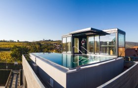 Dachpool mit Glasw&auml;nden auf einem modernen Geb&auml;ude, umgeben von Landschaft.