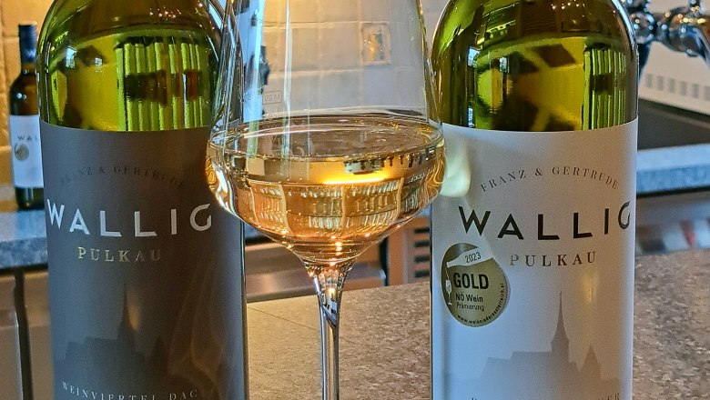 Zwei Weinflaschen und ein Glas Weißwein auf einer Theke.