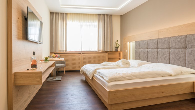 Gästezimmer, © Fam Breitenfelder / Podolsky Modernes Gästezimmer mit Doppelbett, Flachbildfernseher und Holzmöbeln.