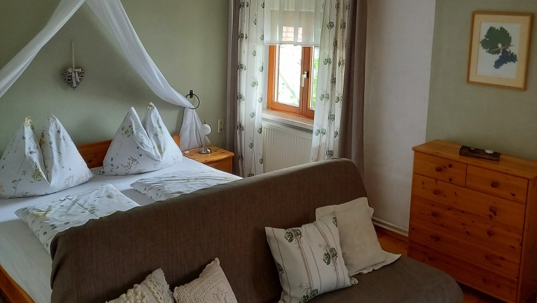 Gemütliches Gästezimmer mit Doppelbett, Sofa und Holzmöbeln.
