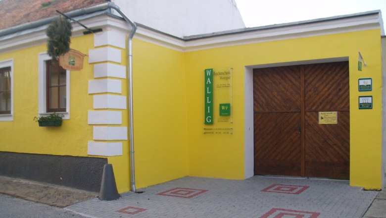 Gelbes Gebäude mit Holztor und Schild 'Wallig'.