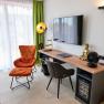 Wohnzimmer mit Sessel, Schreibtisch, Buddha-Statue und Fernseher.