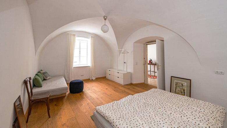 Gewölbezimmer am Hauptplatz, © Fam. Heichinger Gewölbezimmer mit Holzboden, Bett, Sofa und Fenster.