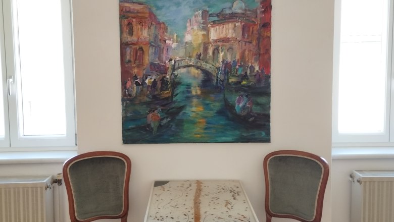 Zwei Stühle und ein Tisch vor einem Gemälde an einer weißen Wand.