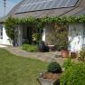 Haus mit Solarpanelen und Garten im Vordergrund.