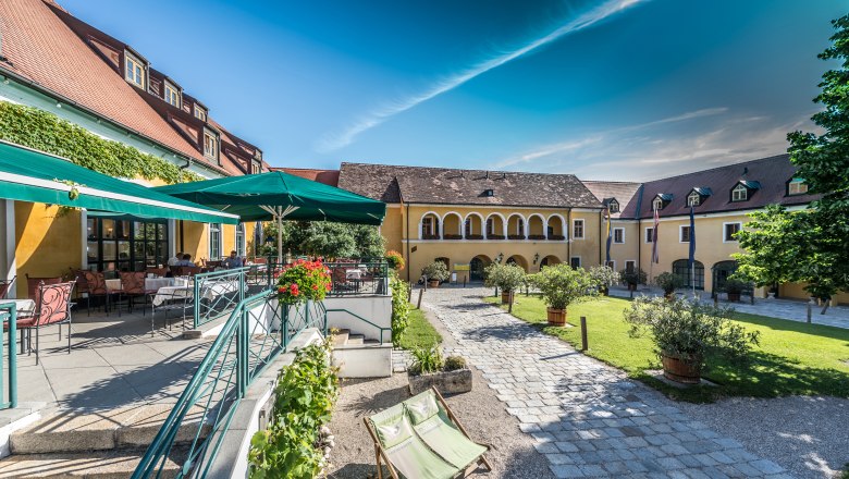 Innenhof des Althof Retz mit Terrasse, Sonnenschirmen und Gartenmöbeln.