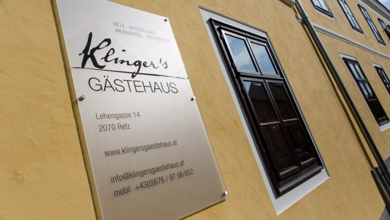 Schild von Klinger's Gästehaus an einer gelben Hauswand.