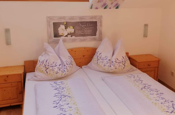 Gemütliches Schlafzimmer mit Dachfenstern und Blumenbettwäsche.