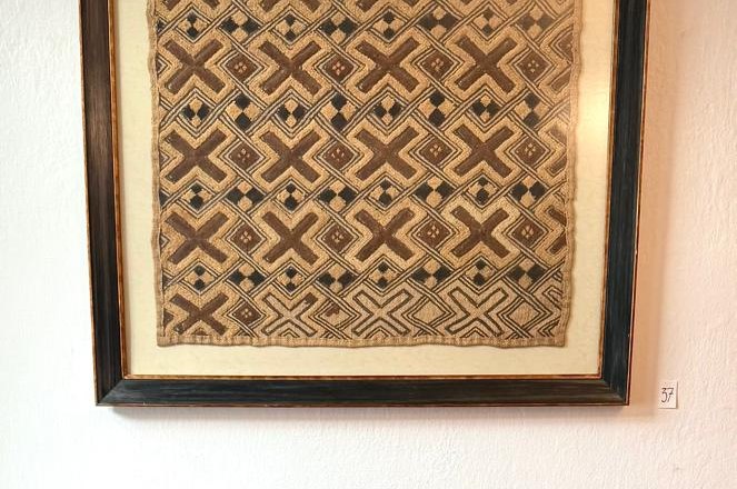 Rotes Sofa vor einem gerahmten, gemusterten Kunstwerk an der Wand.