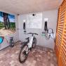Fahrrad in einer Garage mit Ladestation und Wandbild eines Radfahrers in einem Weinberg.
