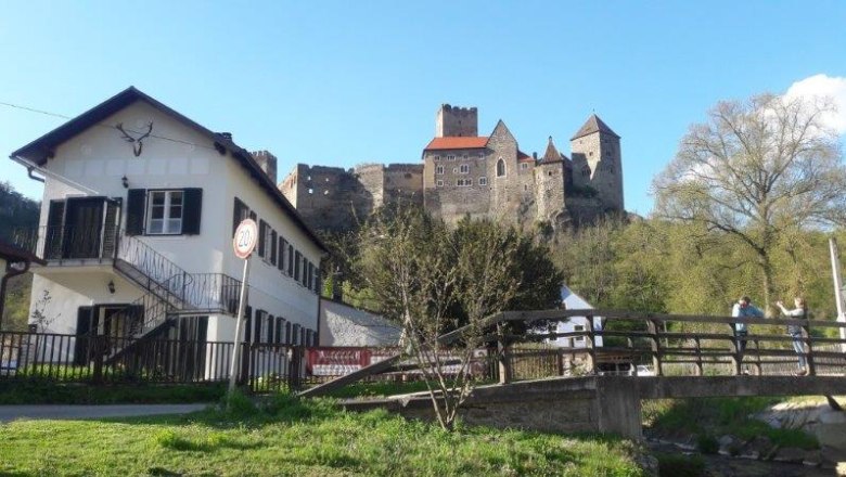 Ein Haus mit Hirschgeweih und eine Burg im Hintergrund.