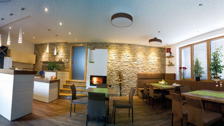 Verkostungsraum, © Fam. Wagner Ein moderner Verkostungsraum mit Holzmöbeln, Steinwand, Kamin und Pflanzen.