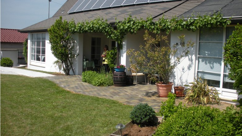 Haus mit Solarpanelen und Garten im Vordergrund.