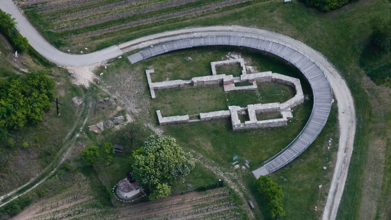 Luftaufnahme einer archäologischen Ausgrabungsstätte mit einem halbkreisförmigen Steg.