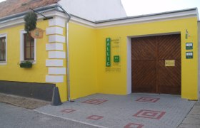 Gelbes Gebäude mit Holztor und Schild 'Wallig'.