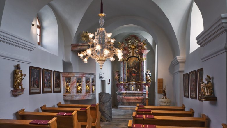 Innenansicht einer barocken Kirche mit Altar, Gem&auml;lden und einem Kronleuchter.