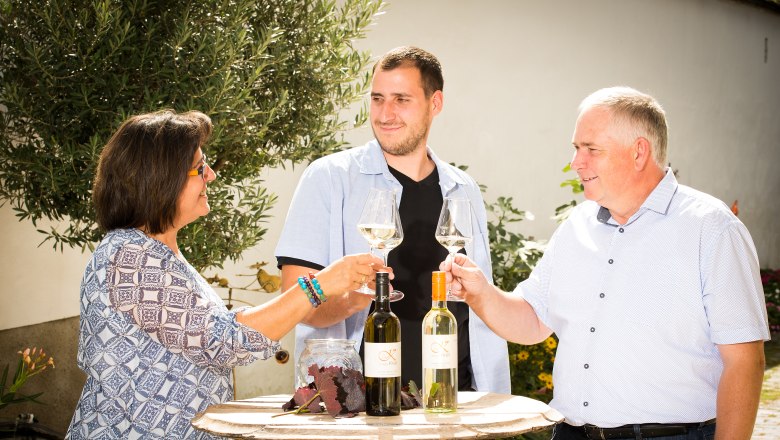 Familie Krell prostet sich mit einem Glas Wein im Innenhof zu.