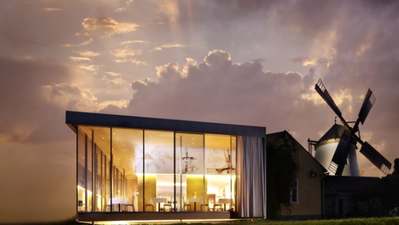 Moderne Glasarchitektur neben einer traditionellen Windm&uuml;hle bei Sonnenuntergang.