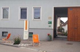 Eingang eines Weinguts mit Schild 'Krell', Liegestuhl und Pflanzen.