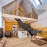 Modernes Loft mit offener Galerie, gelbem Sofa und Holzelementen.